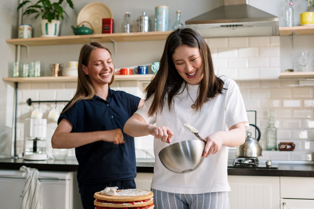 two women laughing and having fun while practicing their gluten-free baking