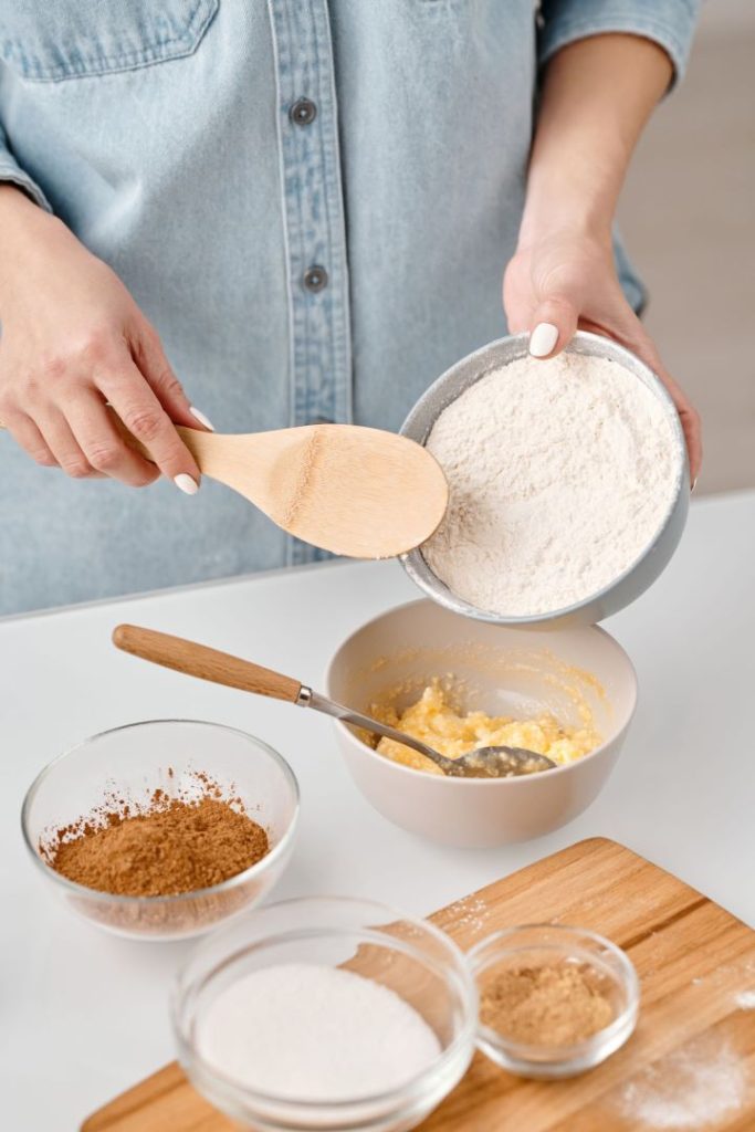 Baker adding gluten-free flour to her wet mix
